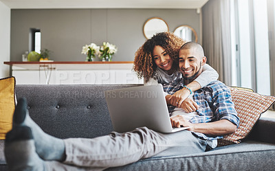 Buy stock photo Shot of a young woman hugging her husband while he uses a laptop on the sofa at home