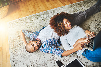Buy stock photo Happy, relaxed and carefree couple bonding together on the living room floor at home. Loving, affectionate and smiling boyfriend and girlfriend relaxing, typing on a laptop and lying down from above