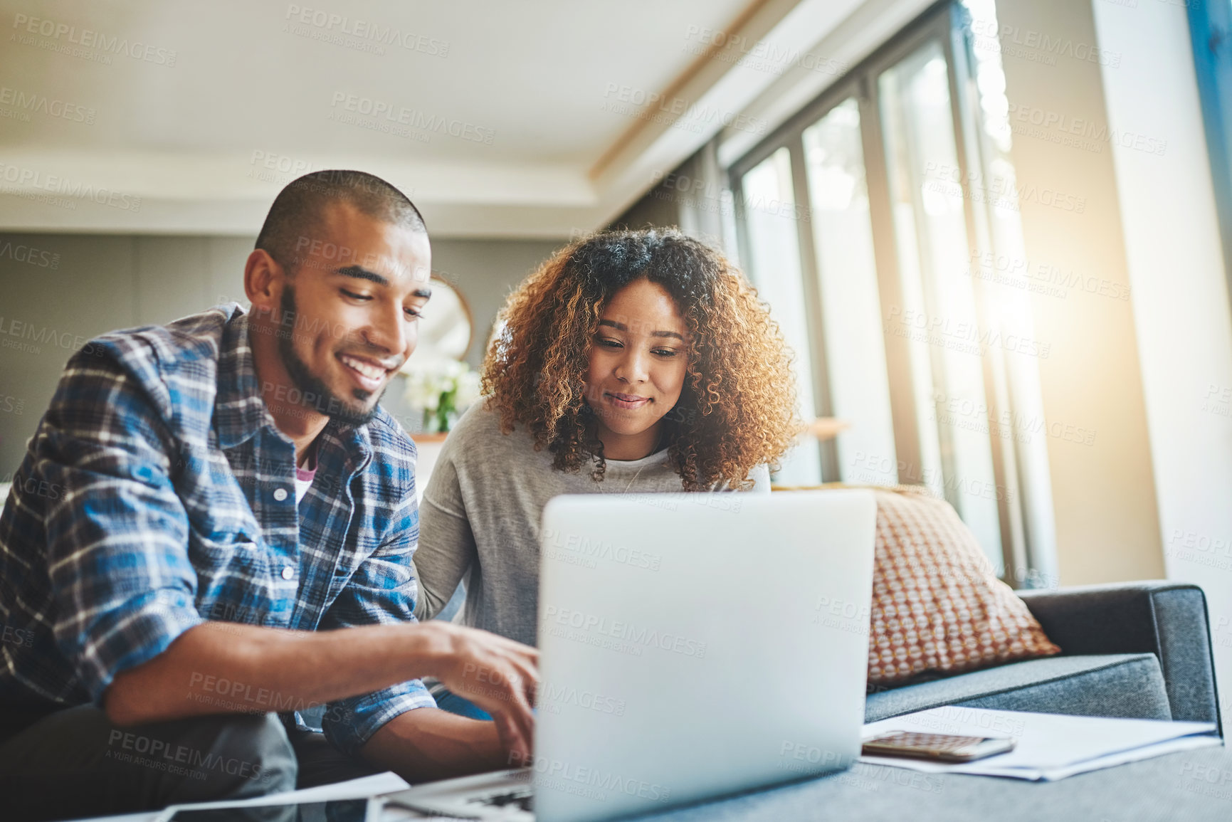 Buy stock photo Shot of a young couple using a laptop while working on their home finances