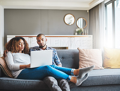 Buy stock photo Relaxed couple relaxing at home using an online streaming service on a laptop and enjoying the day together. Young African American lovers sitting on a couch resting and watching an internet video
