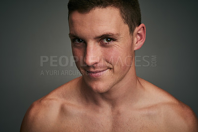 Buy stock photo Studio portrait of a cheerful young shirtless man standing against a grey background while looking into the camera
