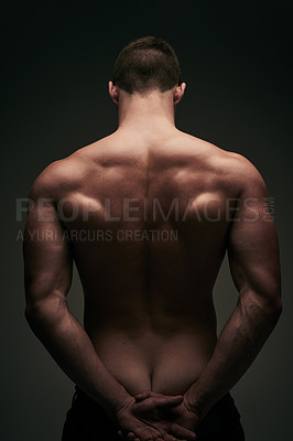 Buy stock photo Rearview shot of a young unrecognizable man standing naked against a grey background with his hands behind his back