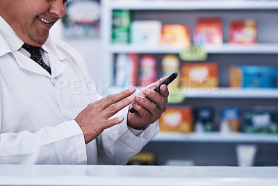 Buy stock photo Shot of an unrecognizable pharmacist using a cellphone in a pharmacy