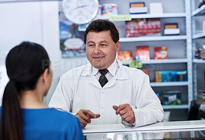 Buy stock photo Shot of a male pharmacist helping a female customer in a pharmacy