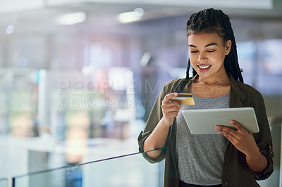 Buy stock photo Shot of a young businesswoman making an online purchase using a tablet at the office