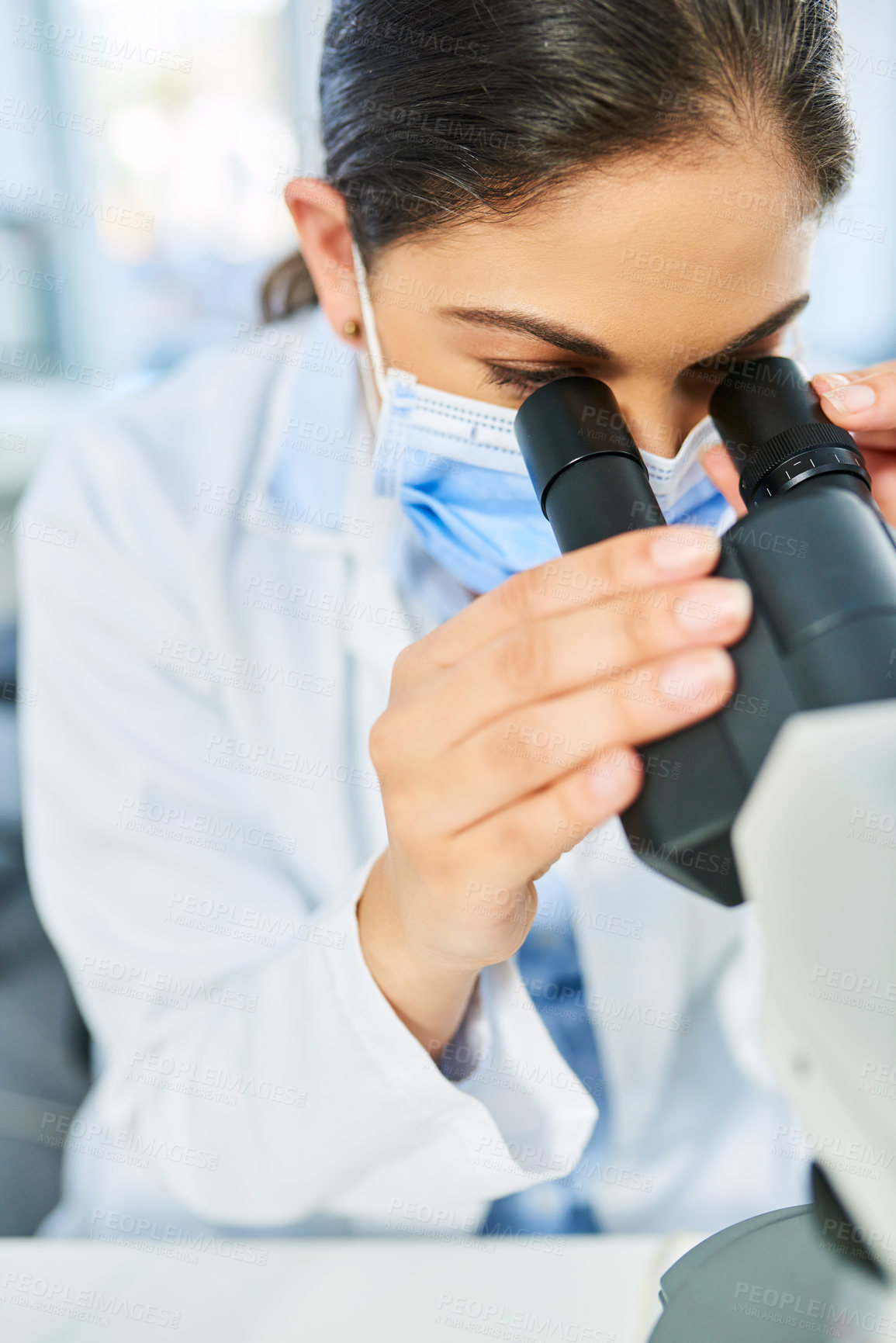 Buy stock photo Shot of a young scientist using a microscope in a lab