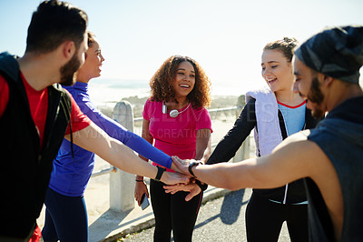 Buy stock photo Shot of a group of young cheerful friends forming a huddle before a fitness exercise outside during the day