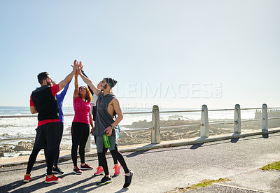 Buy stock photo Shot of a group of young cheerful friends forming a huddle before a fitness exercise outside during the day