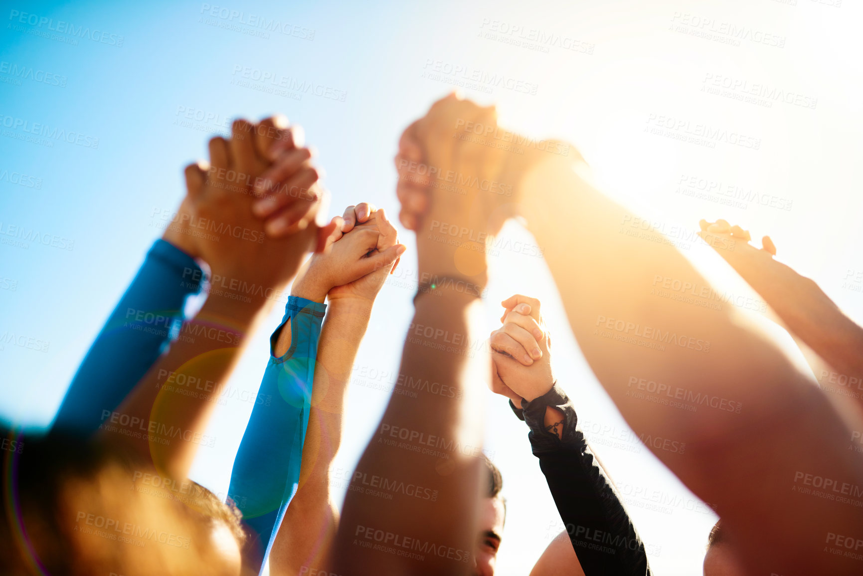 Buy stock photo Shot of a group of unrecognizable people holding hands together in the air
