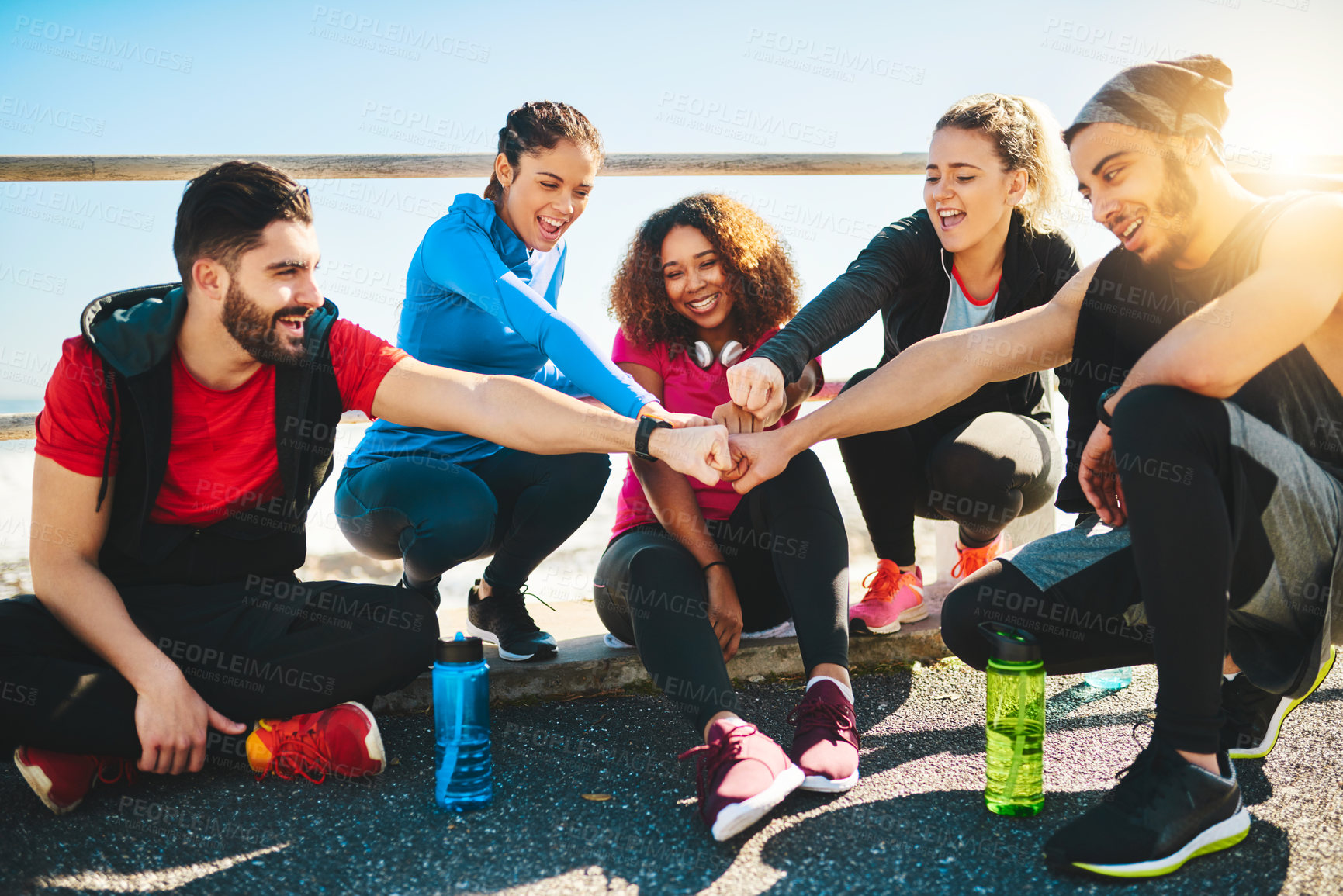 Buy stock photo Shot of a group of young cheerful friends forming a huddle after a fitness exercise outside during the day