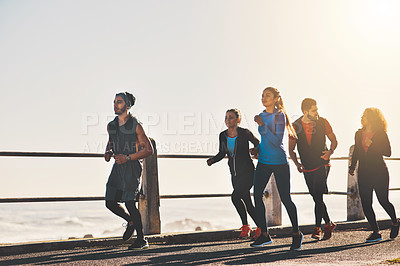 Buy stock photo Shot of a fitness group out running on the promenade