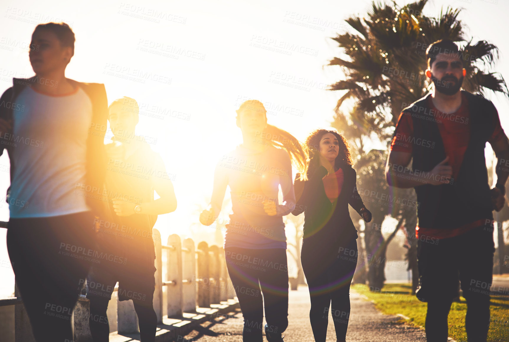 Buy stock photo Shot of a fitness group out running on the promenade
