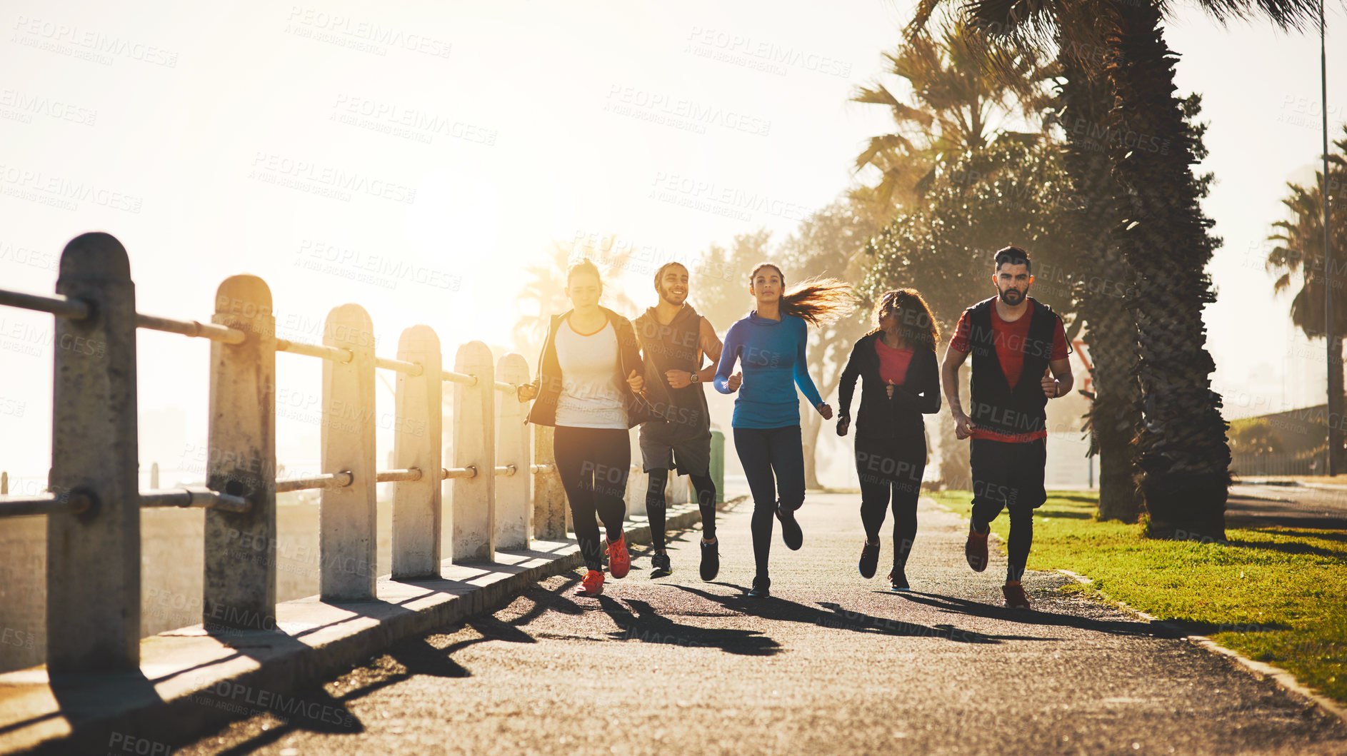 Buy stock photo People, fitness or running with sunset on promenade for cardio workout or exercise together by beach. Active team, community or group of runners in race for sprint or marathon on sidewalk by ocean