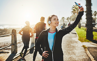 Buy stock photo Cropped shot of a sporty young woman taking a selfie while out on the promenade