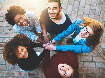 Buy stock photo High angle portrait of a diverse group of college friends standing outside with their hands in a huddle