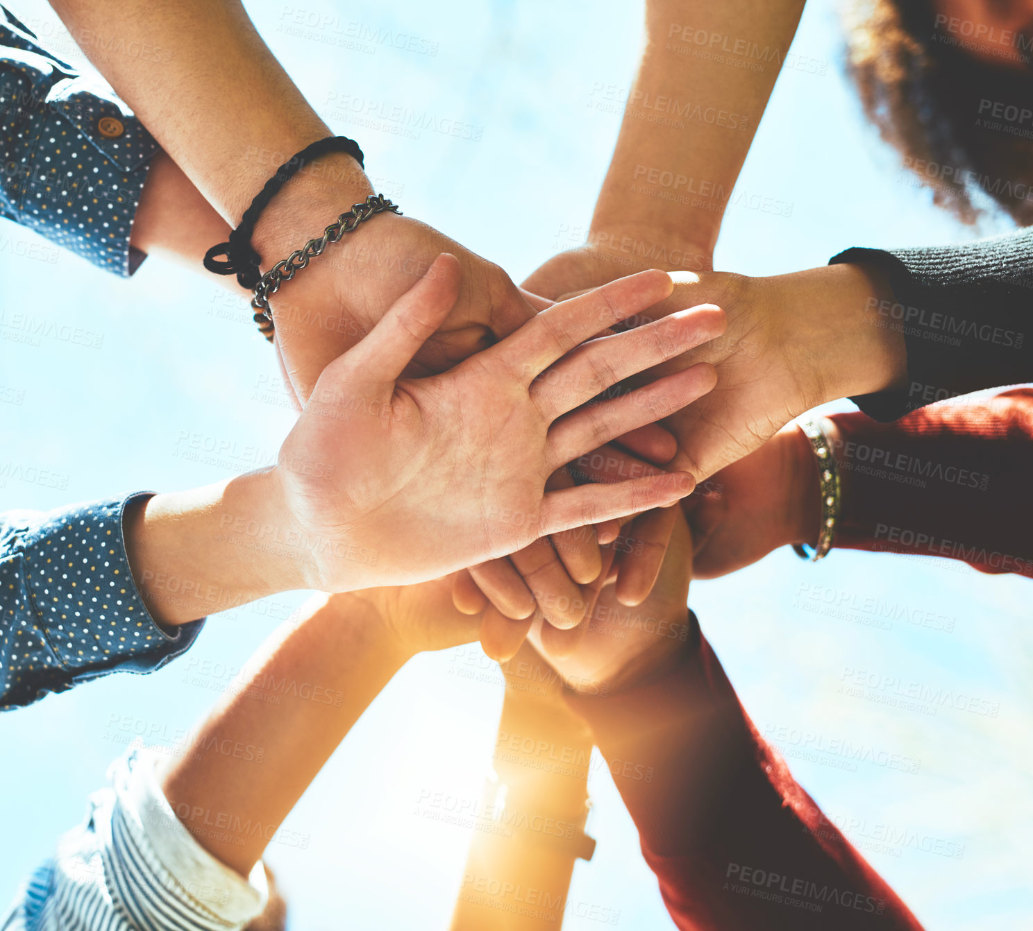 Buy stock photo High angle shot of an unrecognizable group of college friends standing outside with their hands in a huddle