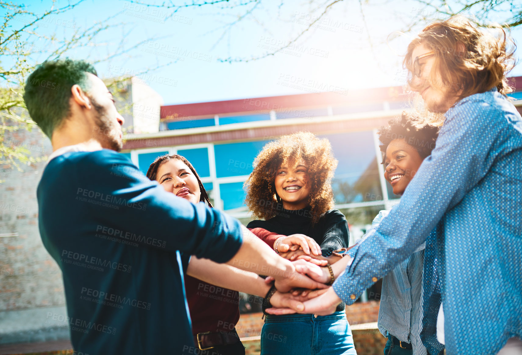 Buy stock photo Cropped shot of a diverse group of college friends standing outside with their hands in a huddle