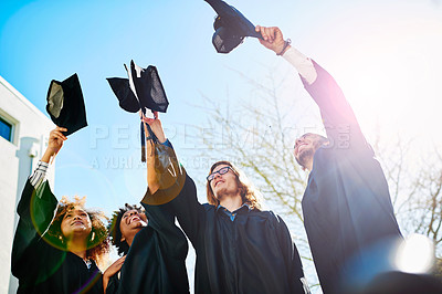 Buy stock photo Cropped shot of a group of students throwing their caps into the air after graduating
