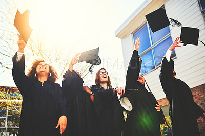 Buy stock photo Cropped shot of a group of students throwing their caps into the air after graduating