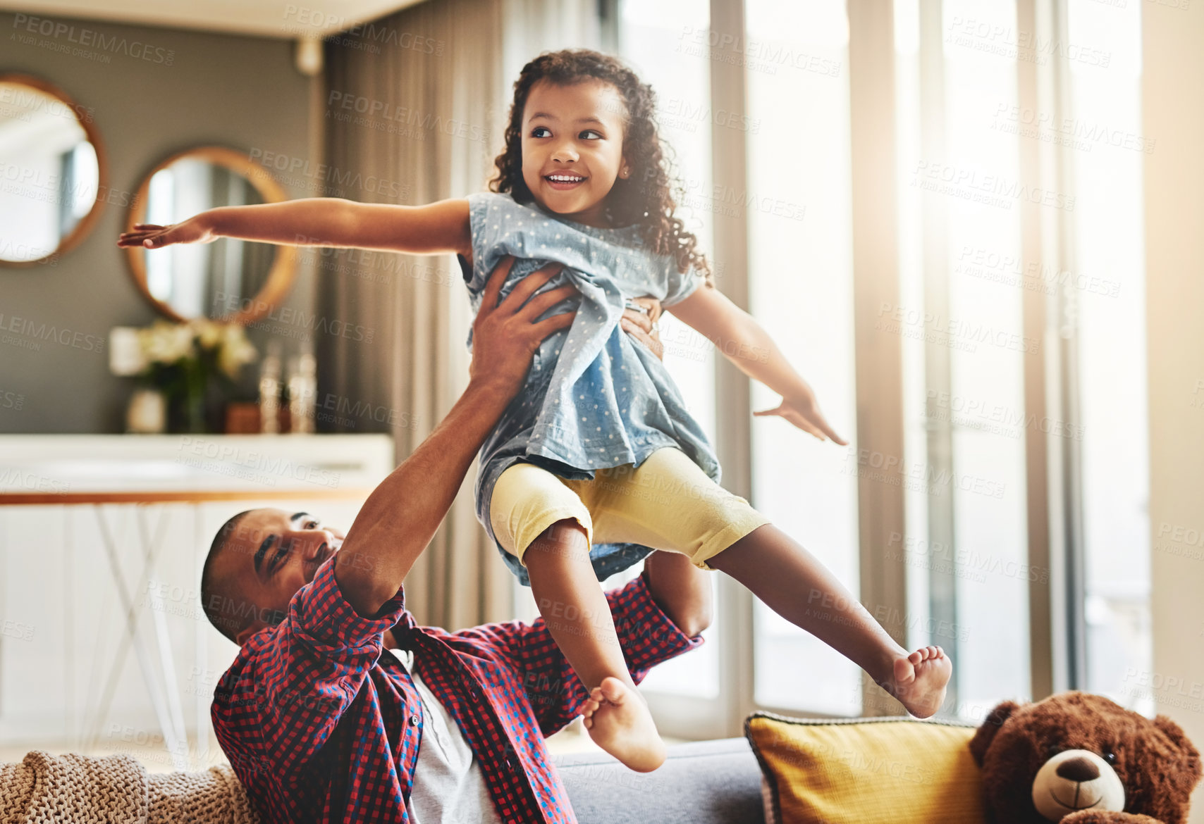 Buy stock photo Shot of an adorable little girl and her father playing together on the sofa at home