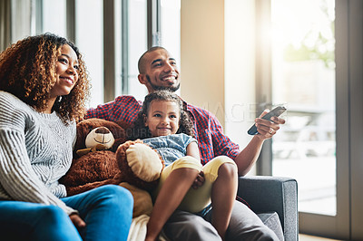 Buy stock photo Shot of a happy young family of three watching tv from the sofa at home