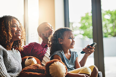 Buy stock photo Shot of a happy young family of three watching tv from the sofa at home