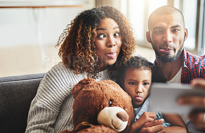 Buy stock photo Shot of an adorable little girl taking selfies with her parents at home on a mobile phone