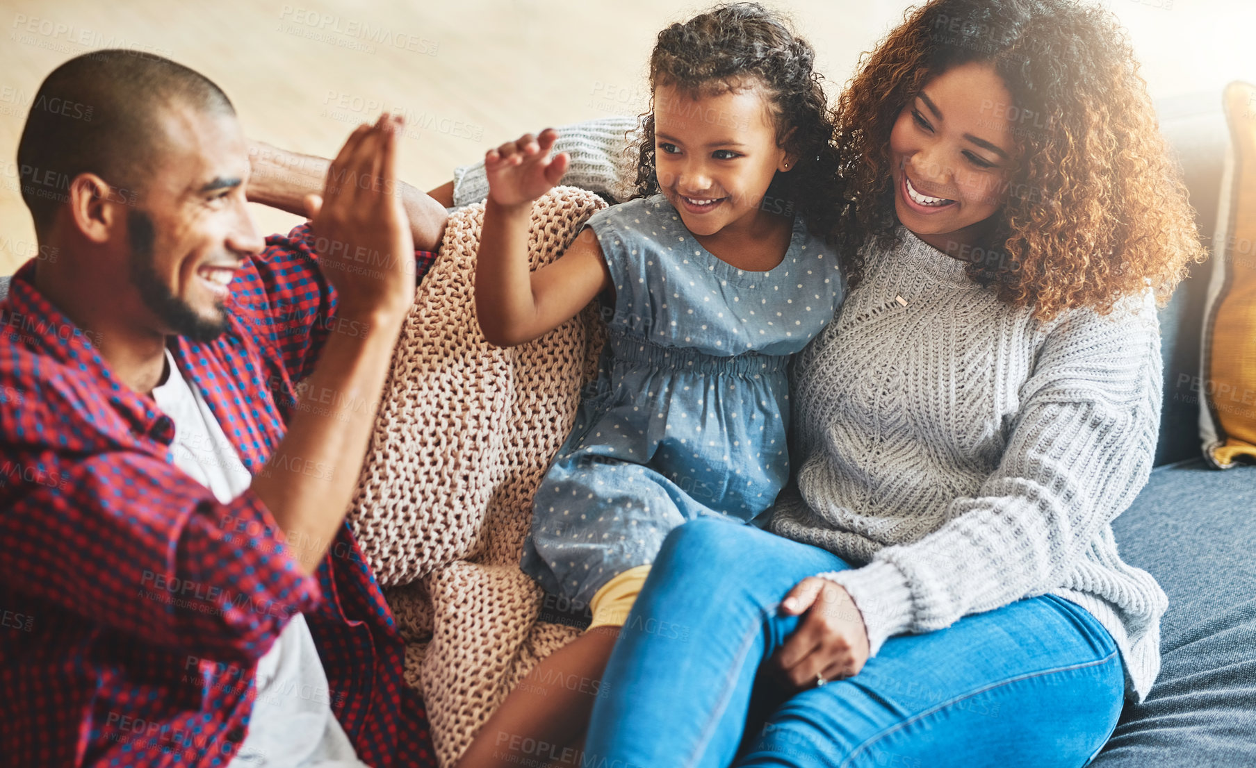 Buy stock photo Shot of an adorable little girl and her parents playing together on the sofa at home