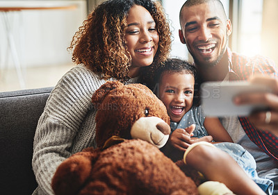 Buy stock photo Shot of an adorable little girl taking selfies with her parents at home on a mobile phone
