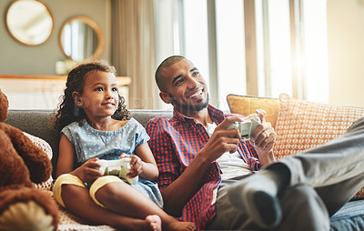 Buy stock photo Shot of an adorable little girl and her father playing video games together on the sofa at home