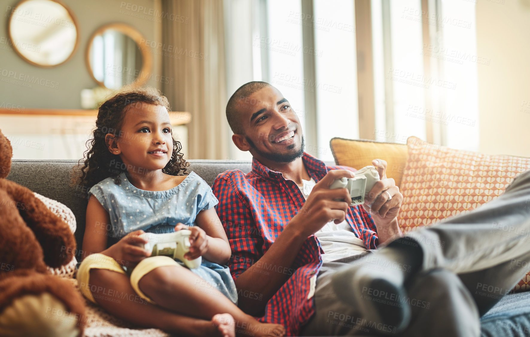 Buy stock photo Shot of an adorable little girl and her father playing video games together on the sofa at home