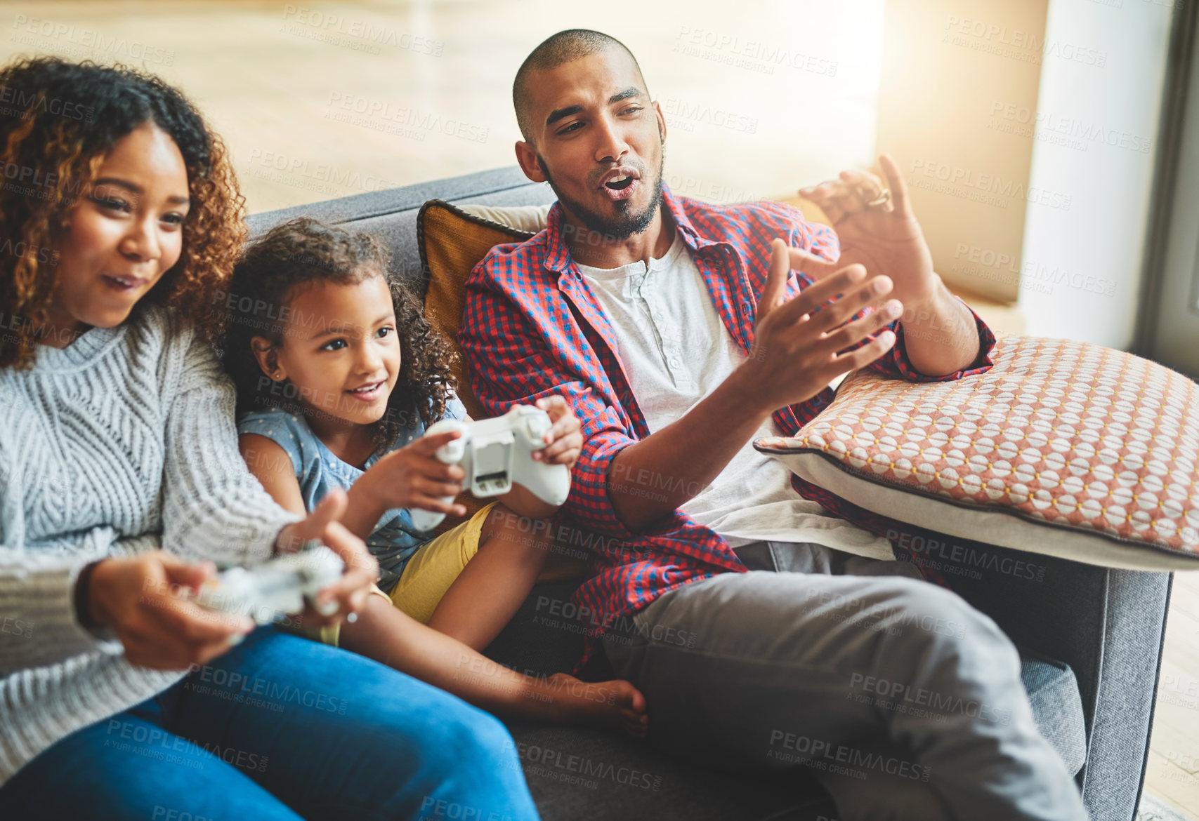 Buy stock photo Shot of an adorable little girl and her parents playing video games together on the sofa at home