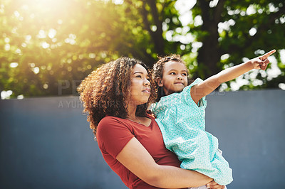 Buy stock photo Shot of an adorable little girl showing her mother something in their backyard
