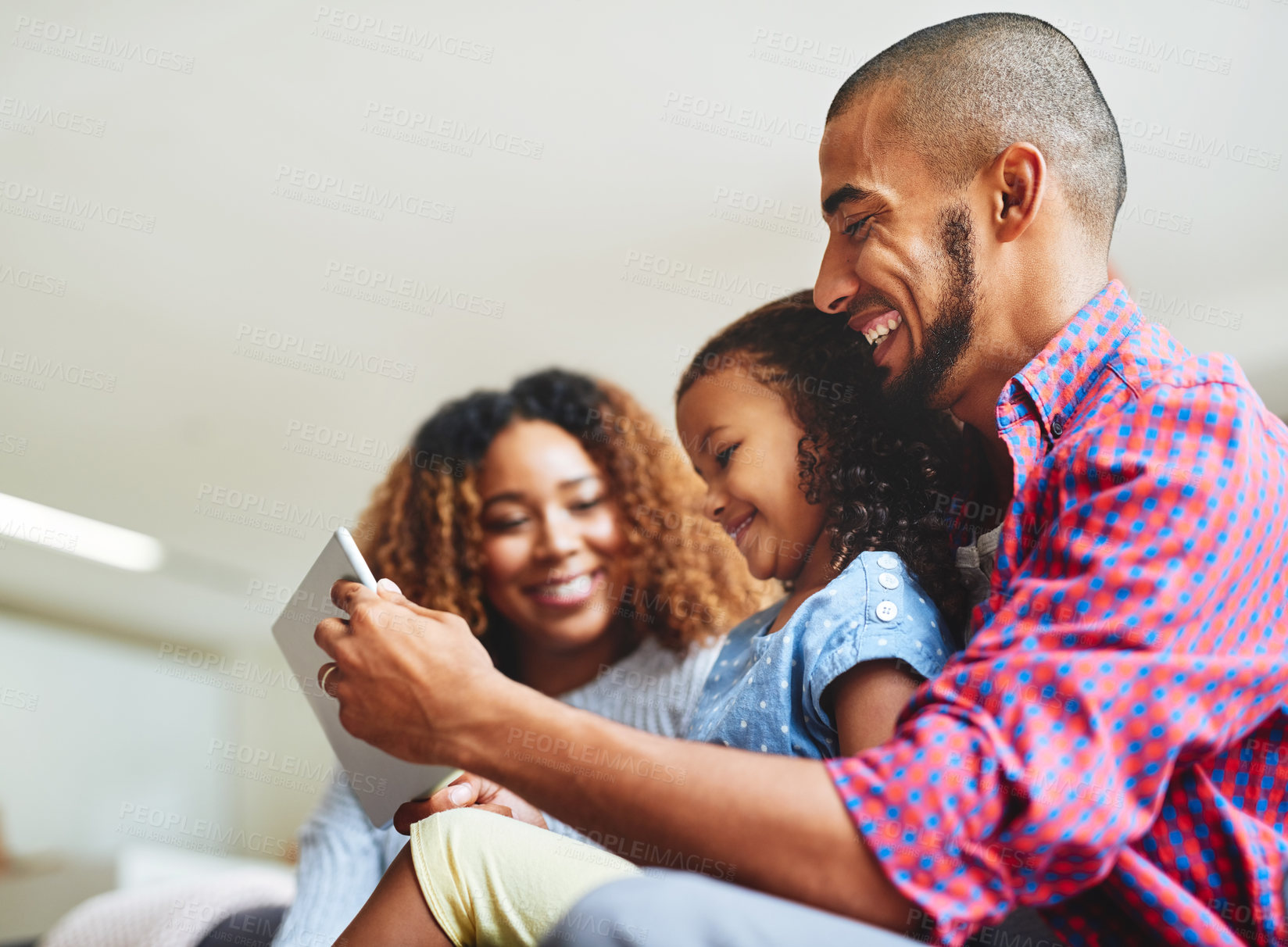 Buy stock photo Shot of an adorable little girl and her parents using a digital tablet together on the sofa at home
