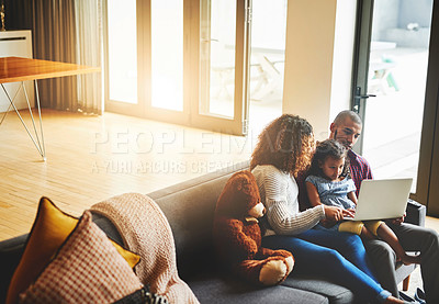 Buy stock photo Shot of an adorable little girl and her parents using a laptop together on the sofa at home
