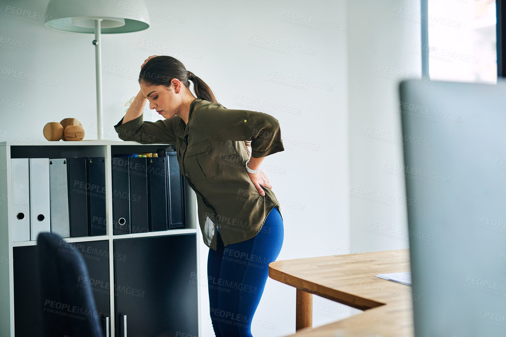 Buy stock photo Shot of a young businesswoman suffering with back pain in an office