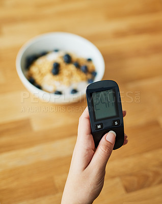 Buy stock photo Closeup shot of an unrecognizable woman testing her blood sugar level with a glucose meter before breakfast
