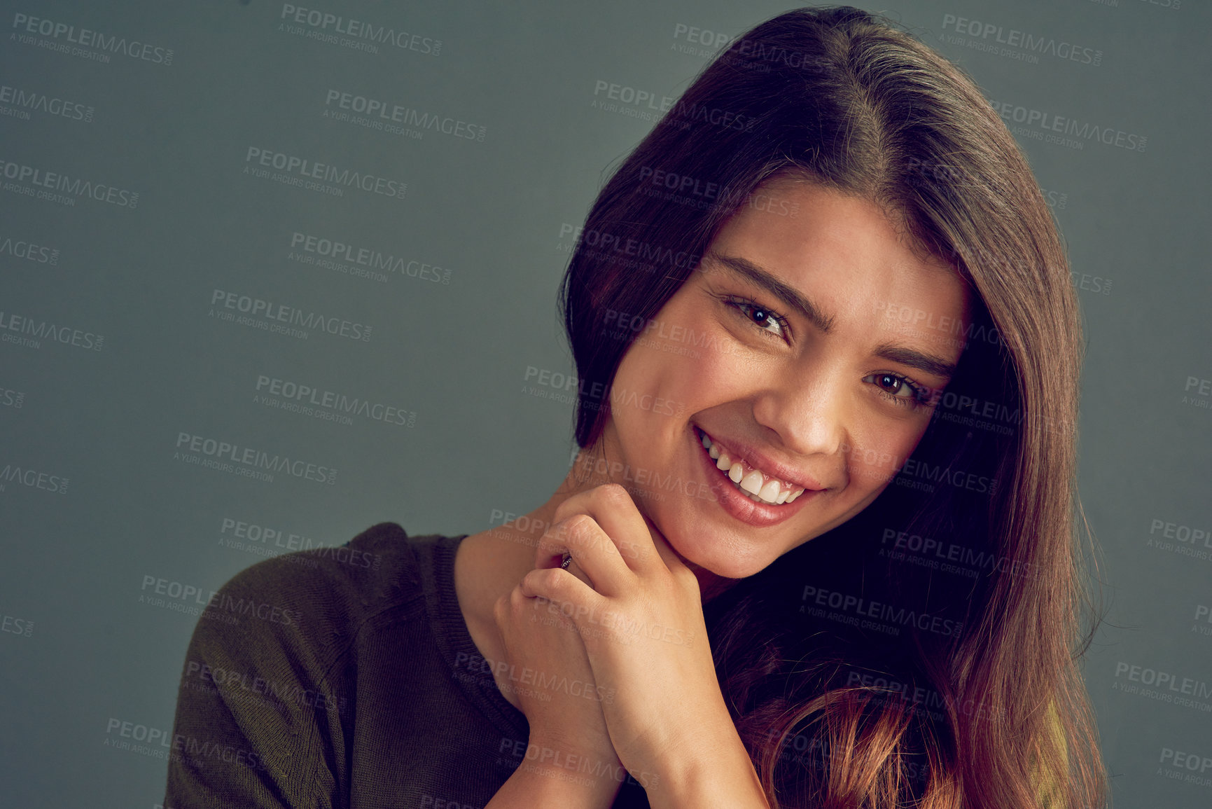 Buy stock photo Studio shot of an attractive and cheerful young woman posing against a gray background while looking into the camera