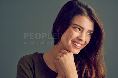 Buy stock photo Studio shot of an attractive and cheerful young woman posing against a gray background while looking into the camera