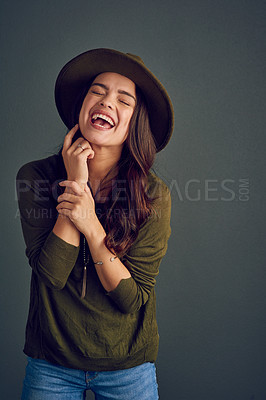 Buy stock photo Studio shot of a carefree young woman posing with a hat while standing against a dark background