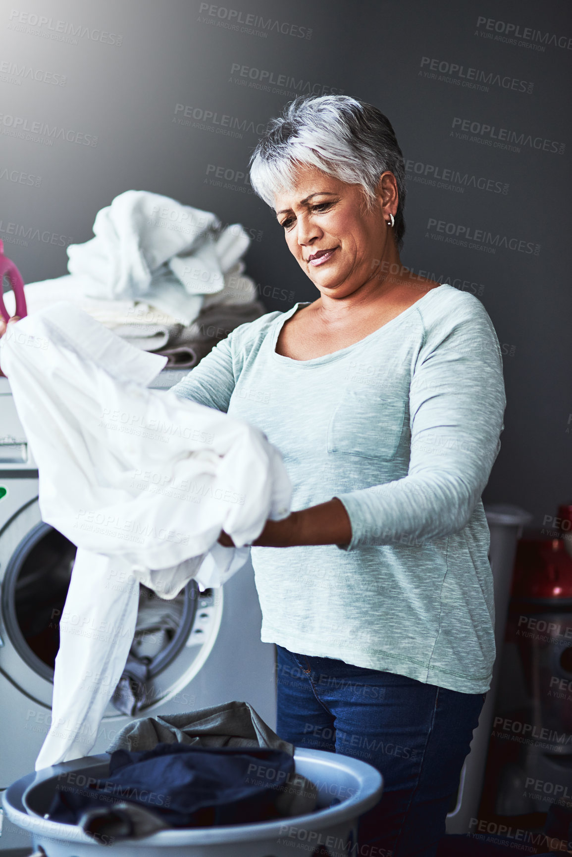 Buy stock photo Shot of a mature woman doing laundry at home