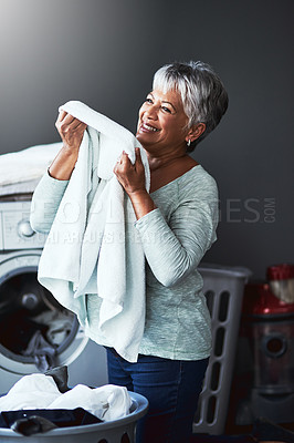 Buy stock photo Shot of a mature woman smelling freshly washed towels while doing laundry at home