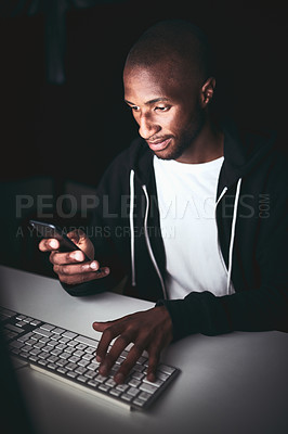 Buy stock photo High angle shot of a young man using his cellphone while working late in the office