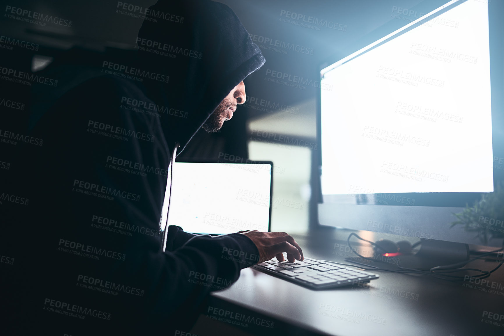 Buy stock photo Cropped shot of a young male hacker cracking a computer code in the dark