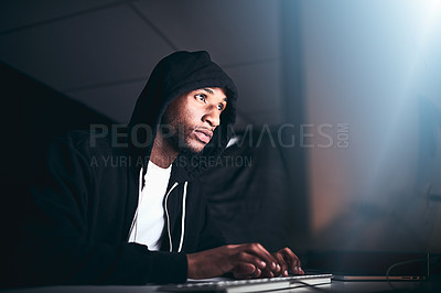 Buy stock photo Low angle shot of a young male hacker cracking a computer code in the dark