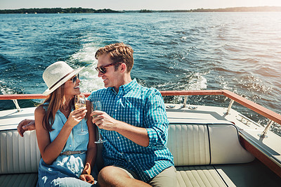 Buy stock photo Shot of a young couple having champagne on a boat ride