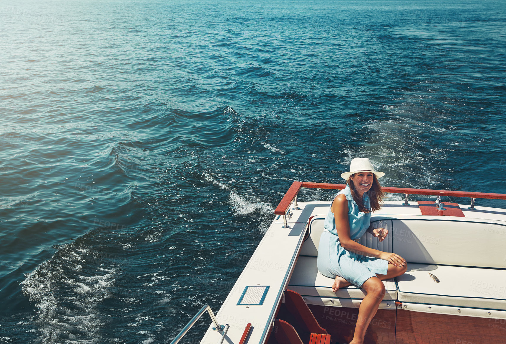 Buy stock photo High angle portrait of an attractive young woman sitting at the back of a yacht on the open seas