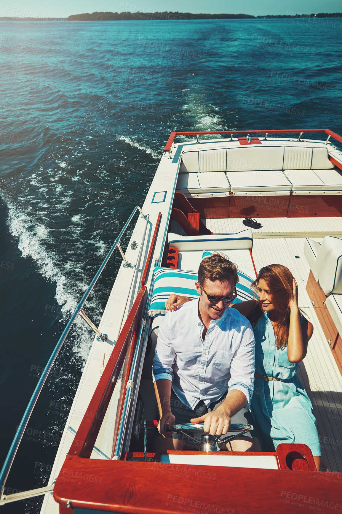 Buy stock photo High angle shot of an affectionate young couple sailing on the open seas in their yacht