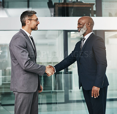 Buy stock photo Shot of two businessmen shaking hands in an modern office