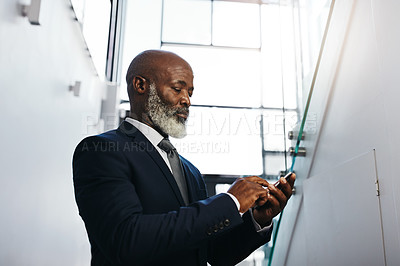Buy stock photo Cropped shot of a mature businessman using his cellphone in an office